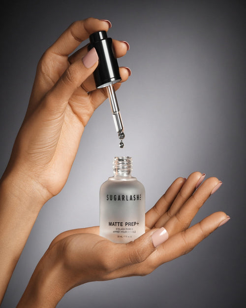 Model holding a bottle of Matte Prep+ mattifying eyelash extensions ex primer with dropper applicator.