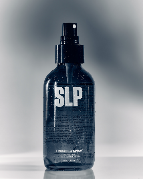 A bottle of Finishing Spray covered in small water droplets used for skin and eyelash extensions