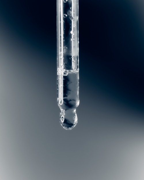 A dropper with Control Eyelash Glue Accelerator dripping out.