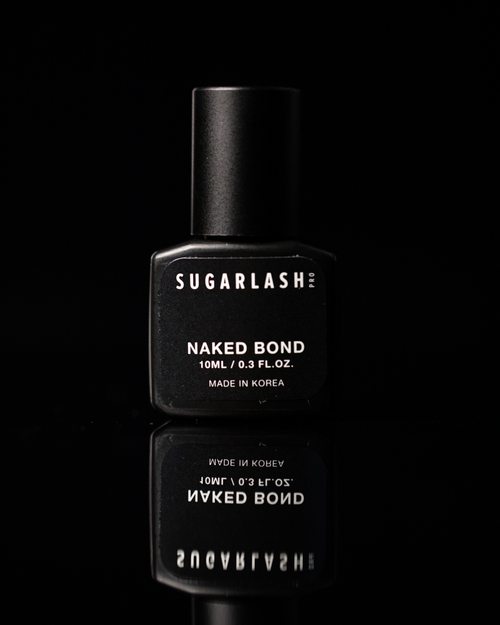 A bottle of Naked Bond eyelash glue with its reflection under the bottle.