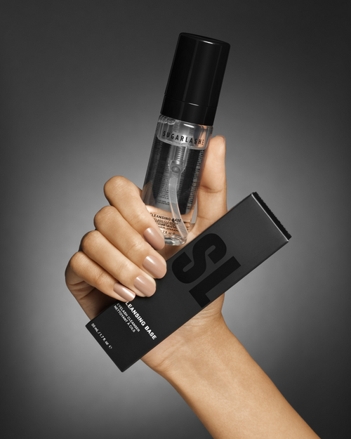 A model holding a bottle of lash extensions cleansing base and the product package.