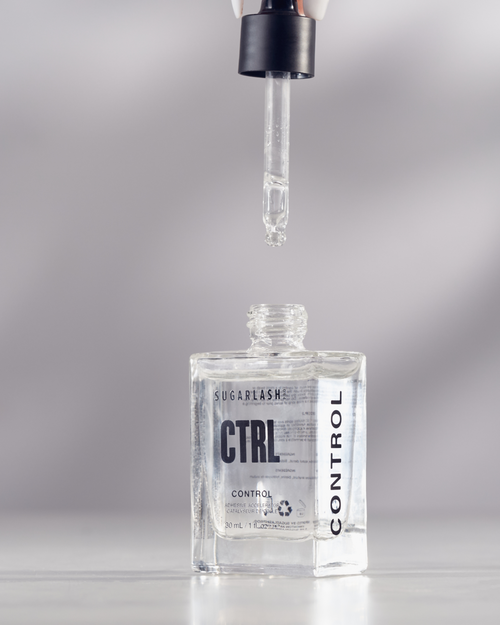 A model holding the dropper applicator above the eyelash glue accelerator bottle.
