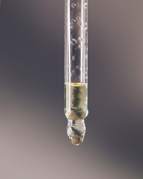 An image of a dropper with Curator, an eyelash extensions solution dripping out.