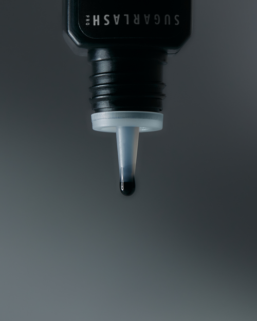 A drop of Bond Noir eyelash extension glue dripping out of the dropper.