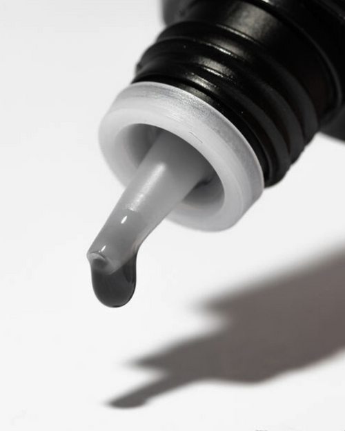 A drop of glue coming out of a bottle of eyelash extension glue.