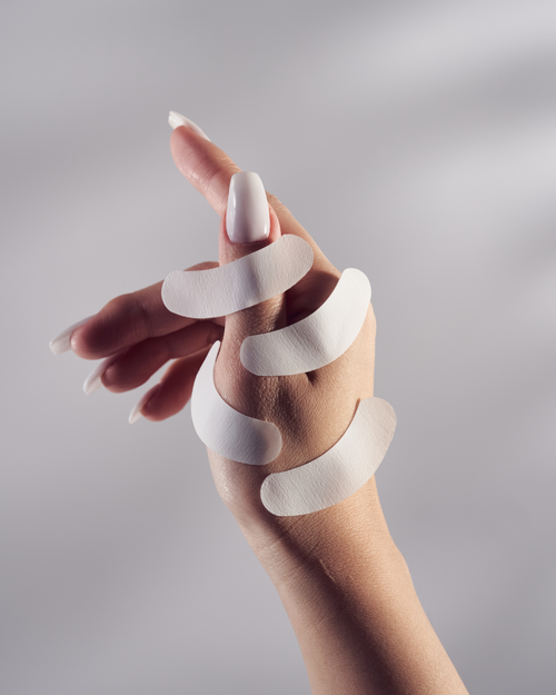 A model's hand with multiple Gel Free Eye Pads stuck to her hand for eyelash extensions.