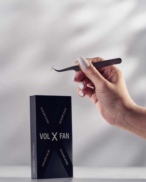A model holding tweezers above a tray of VOL-X Loose Pre-made eyelash extensions Fans.